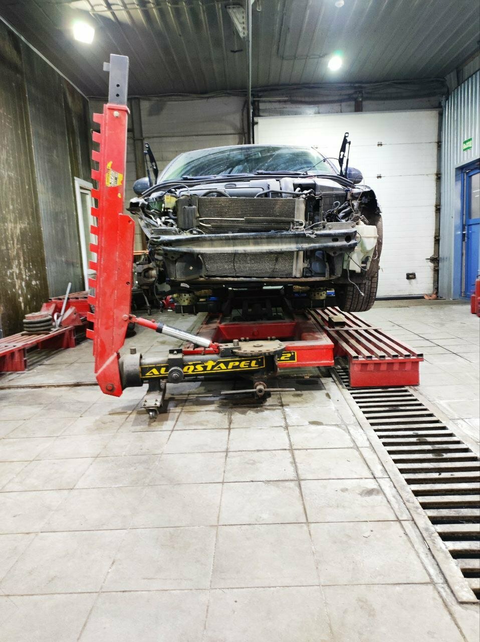 Автомобиль со снятой передней облицовкой на стапеле в кузовном цехе